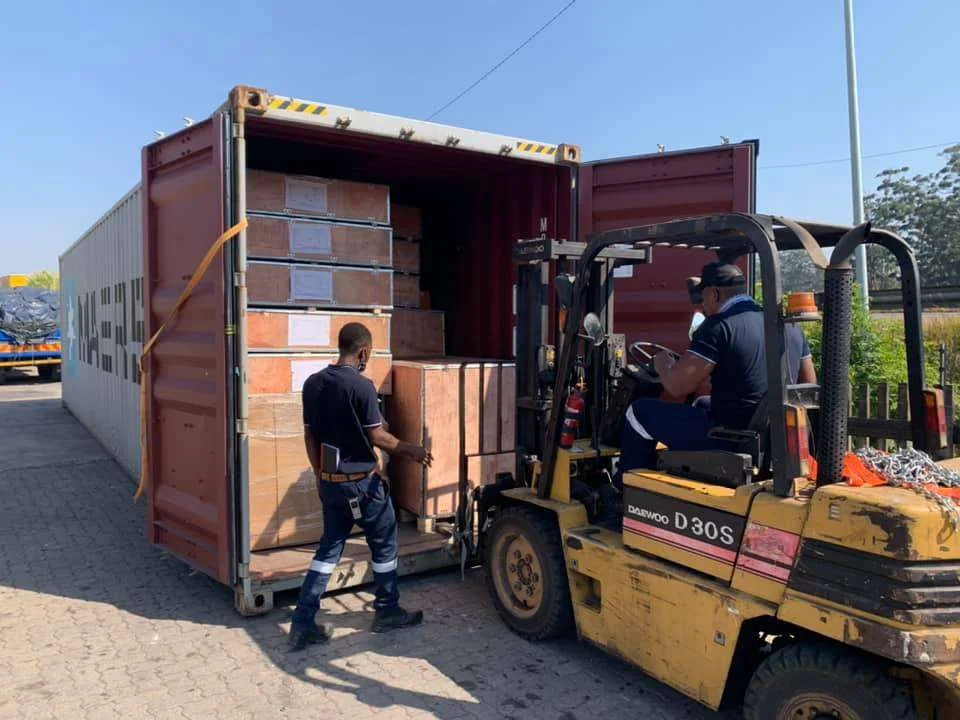 Forklift unloading crated workshop equipment from a shipping container